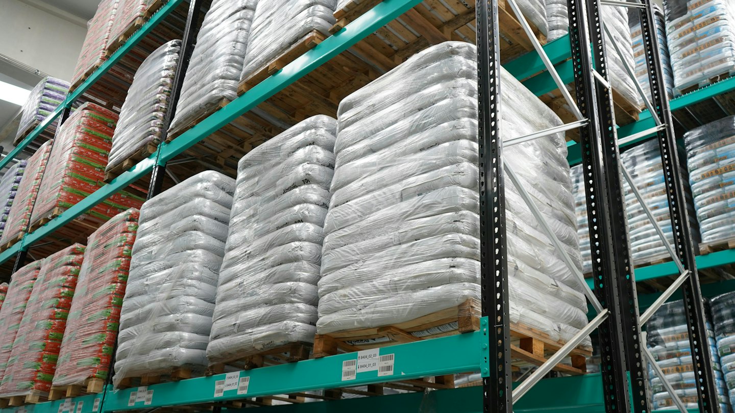 Industriële magazijn vol met goederen op pallets in stellingen.